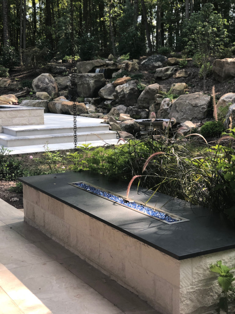 Outdoor stone fire feature beside a water garden