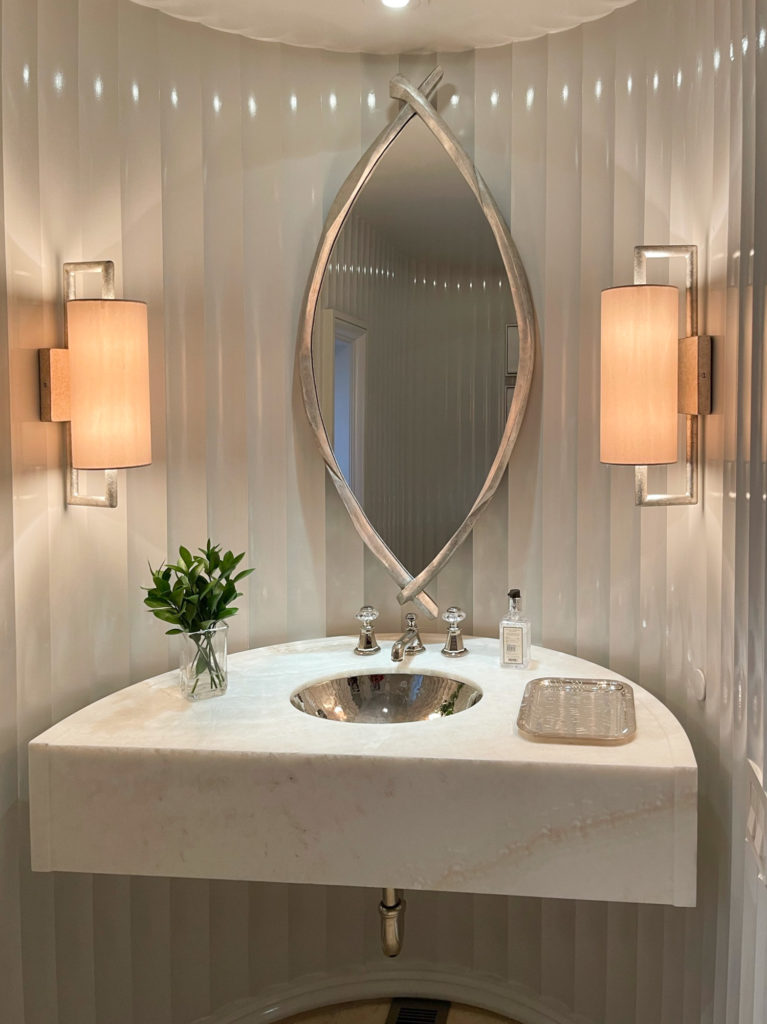 Powder room with a curved stone vanity and sconces