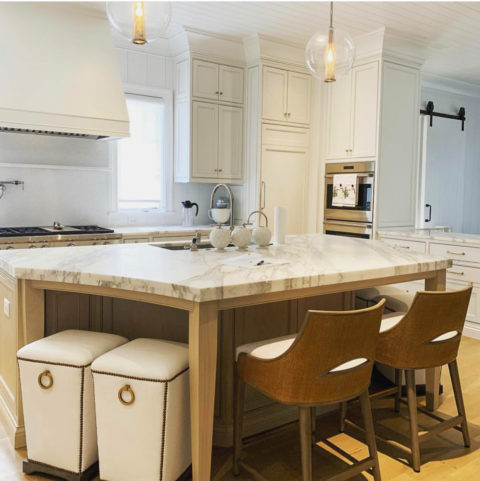 White marble island on a wood base with leather stools